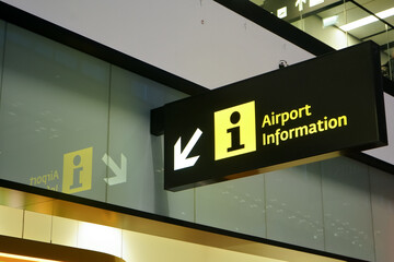 Illuminated Airport information sign with arrow pointing to side, closeup detail