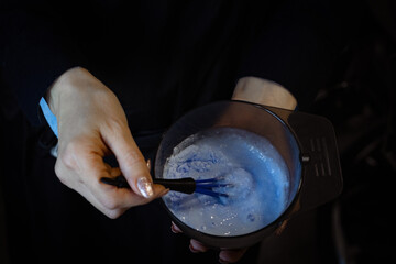 The hairdresser's hands stir the hair dye.