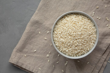 Raw Organic Carnaroli Rice in a Bowl on a gray surface, top view. Overhead, from above, flat lay.