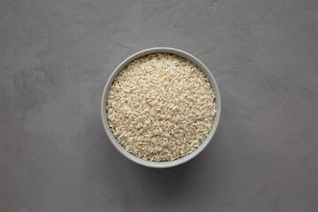 Raw Organic Carnaroli Rice in a Bowl on a gray background, top view. Overhead, from above, flat lay.