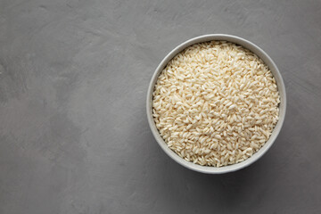 Raw Organic Carnaroli Rice in a Bowl on a gray background, top view. Overhead, from above, flat lay. Space for text.