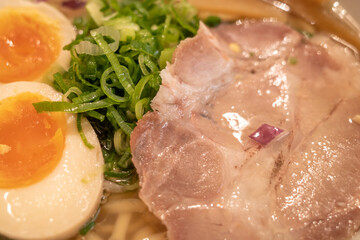 Close up view at chop leek, sliced pork Chash, and boiled egg on the top of Japanese ramen noodle soup. 