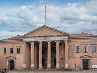 Fototapeta na wymiar Copenhagen, Denmark - July 23, 2022: Light brown facade of Courthouse on Nytorv under blue cloudscape. Pediment and 6 tall columns. Words mean, with law, you build this land,
