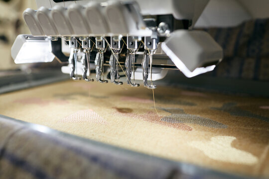Professional embroidery machine making pattern on fabric close up shot