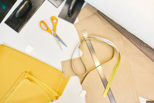 Fabric, scissors, measuring tape, ruler, patterns, chalk and point pressers on table flat lay