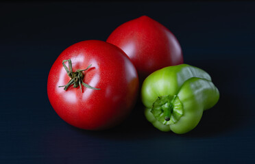 Green bell pepper and tomato on a dark background