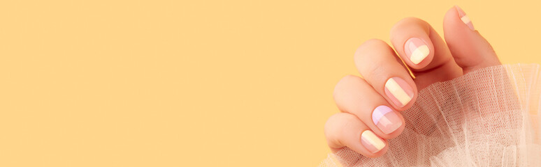 Beautiful females hand with manicure on yellow background. Trendy minimal spring summer nail design