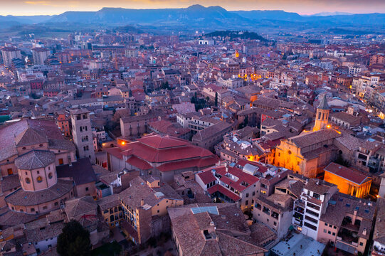 View from drone of Spanish town of Vic with tiled roofs of old buildings and ancient cathedral in winter evening, Barcelona province, Catalonia
