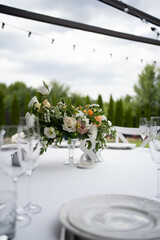 Table centerpiece with white and peach rustic floral arrangement in glass vase. Rustic wedding table.