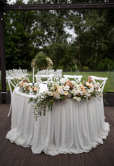 Main table at a wedding reception with beautiful fresh flowers. Outside wedding decorations.