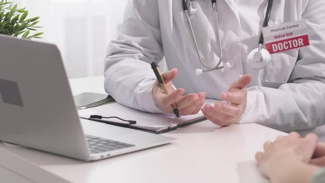 unrecognizable doctor talking to patient during physician appointment female medicine worker gesturing explaining patient prescriptions asking questions for diagnosis. patient's hands moving
