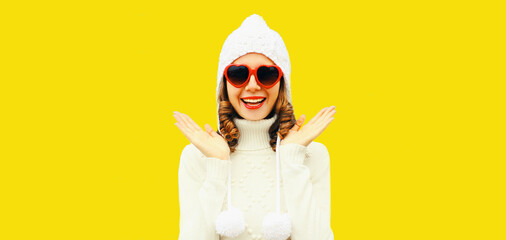 Winter portrait of happy smiling surprised young woman wearing white sweater, knitted hat, red...