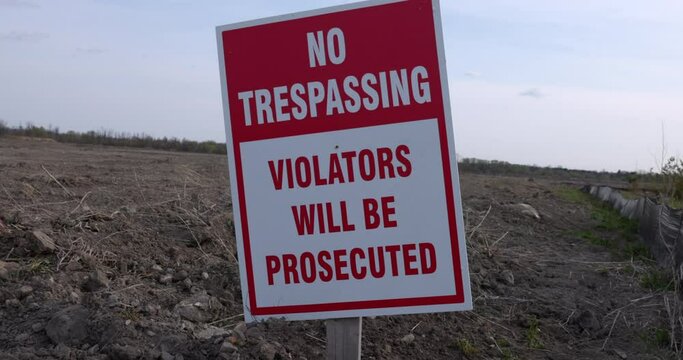 No Trespsassing - violators will be prosecuted sign in front of empty land