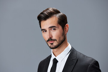 Portrait of a business man in a stylish suit with tie beautiful face on a gray isolated background. Business concept young businessman startup copy space