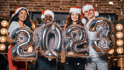 Obraz na płótnie Canvas Happy friends holding silver colored numbers and celebrating Christmas