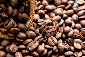 Roasted coffee beans in a cloth sack, on a dark background, close-up image, space for text