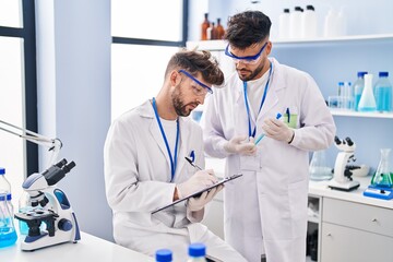 Young couple wearing scientist uniform working at laboratory