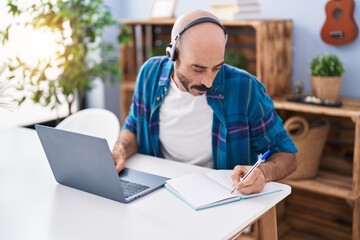 Young hispanic man studying sitting on table at home