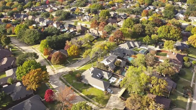 Upscale single family home with swimming pool and colorful fall foliage near Dallas, Texas, America. Aerial view an established suburban residential neighborhood bright autumn leaves, large street