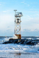 Fototapeta na wymiar Strong surf crashes against the Ocean City Inlet jetty and channel marker after Blizzard Kenan.