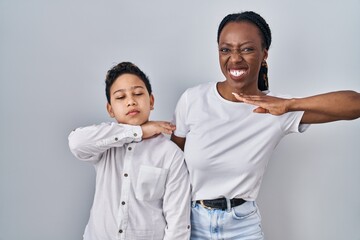 Young mother and son standing together over white background cutting throat with hand as knife, threaten aggression with furious violence