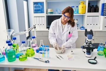 Fototapeta premium Young latin woman wearing scientist uniform working at laboratory