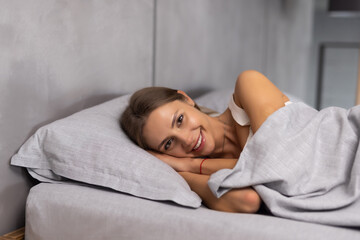 Pretty woman lying down on her bed at home before sleep