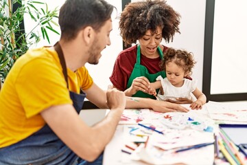 Naklejka premium Couple and daughter smiling confident drawing at art studio