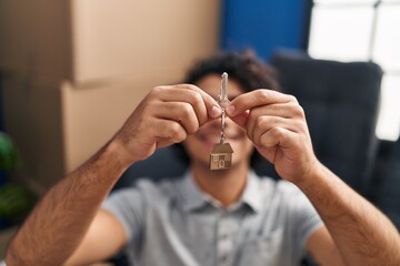 Young hispanic man smiling confident holding key of new house at new home