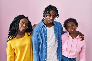 Group of three young black people standing together over pink background looking sleepy and tired,...
