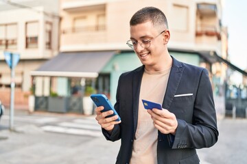 Young hispanic man executive using smartphone and credit card at street