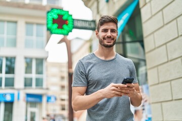 Young caucasian man smiling confident using smartphone at pharmacy