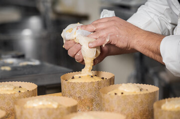 Confectioner topping panettone cakes with piping bag glazed sweet filling. High quality photography