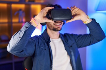 Young caucasian man streamer playing video game using virtual reality glasses at gaming room
