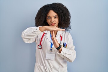 Young african american woman wearing doctor uniform and stethoscope doing time out gesture with hands, frustrated and serious face