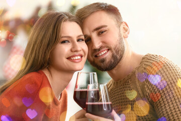 Happy young couple with glasses of wine resting at home