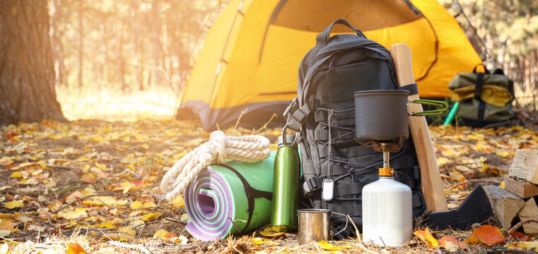 Tourist's survival kit and camping tent in autumn forest