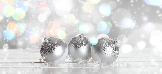 Silver Christmas balls with beads on table against blurred lights