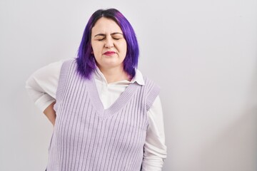 Fototapeta premium Plus size woman wit purple hair standing over white background suffering of backache, touching back with hand, muscular pain