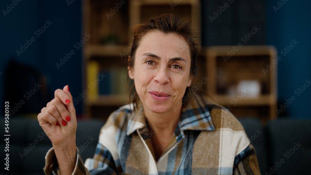 Poster middle age hispanic woman smiling confident sitting on sofa at home