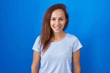Obraz premium Brunette woman standing over blue background with a happy and cool smile on face. lucky person.