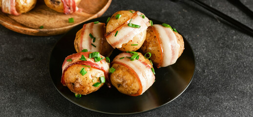 Plate of tasty baked potatoes with bacon on dark background