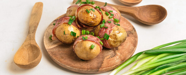 Plate of tasty baked potatoes with bacon on white table