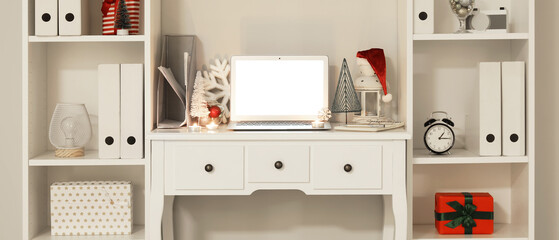 Modern workplace with laptop and Christmas decor in light office