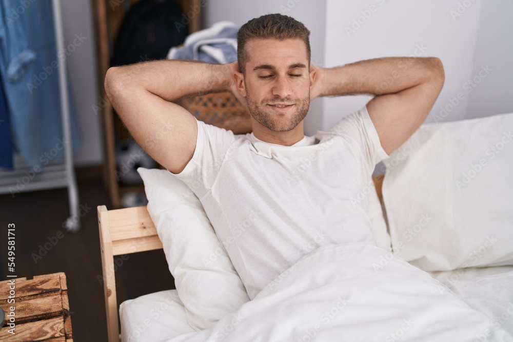 Sticker young caucasian man smiling confident relaxed with hands on bed at bedroom