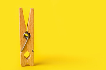Wooden clothespin on yellow background
