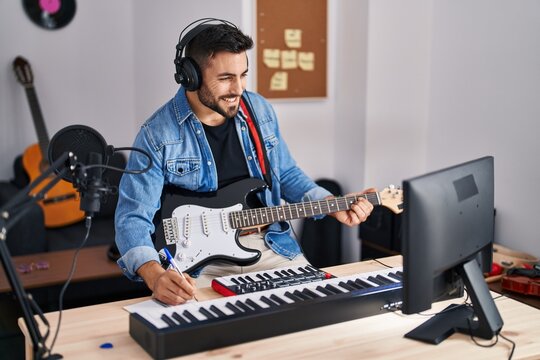 Young hispanic man singing song playing electric guitar at music studio