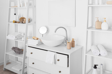 Fototapeta na wymiar Sink and shelf units with bath accessories near white wall