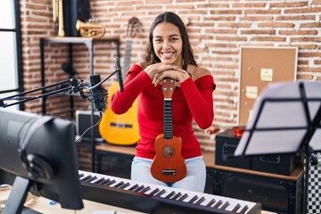 Fototapeta na wymiar Young african american woman musician smiling confident holding ukelele at music studio