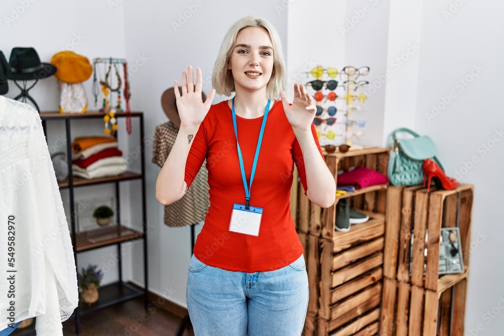 Wall mural young caucasian woman working as manager at retail boutique showing and pointing up with fingers num